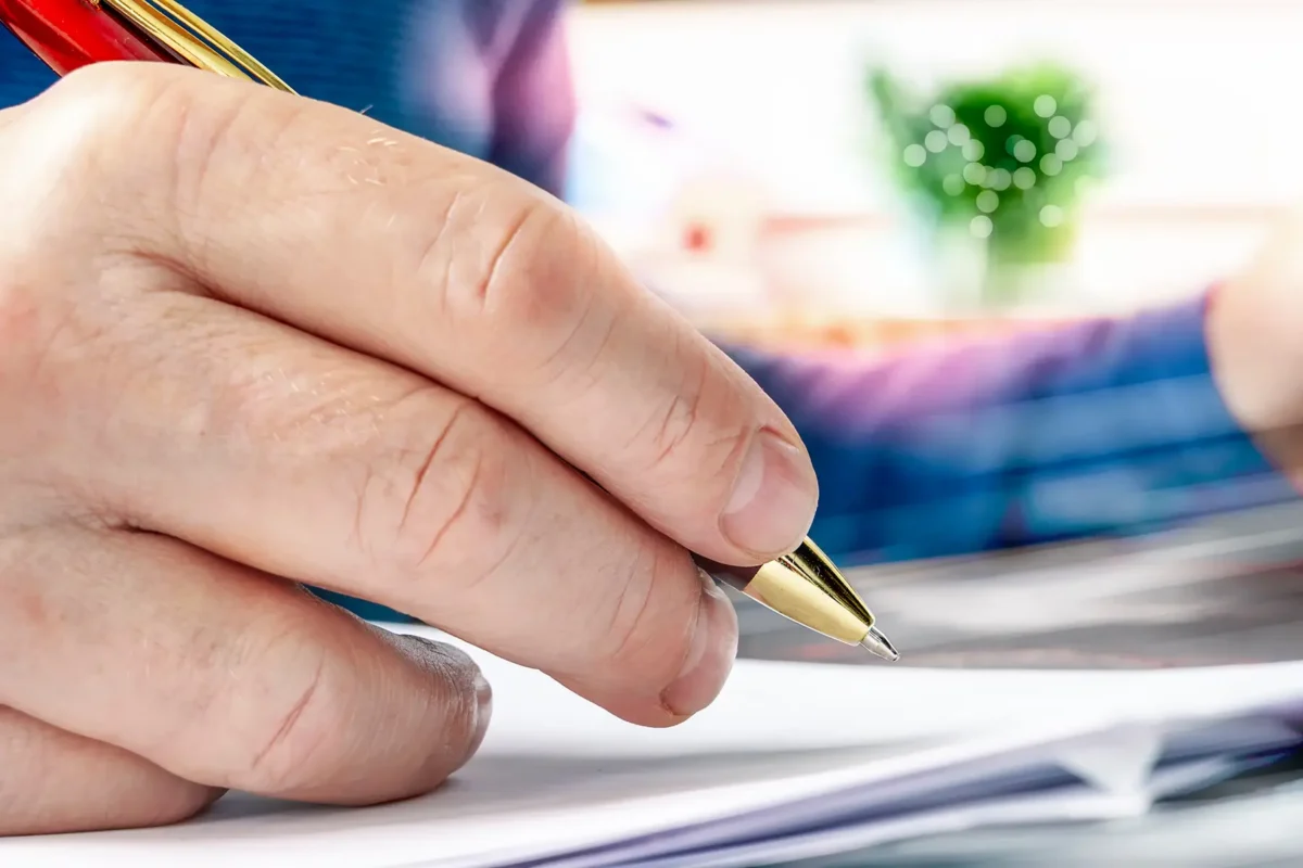 Hand unterschreibt Dokumente für Bestattungsformalitäten
