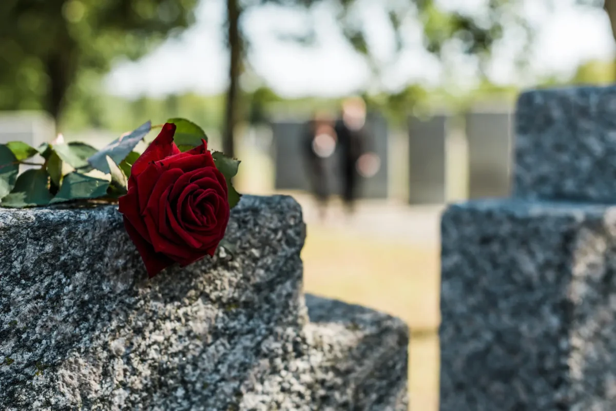 Rote Rose auf Grabstein als Zeichen des Abschieds