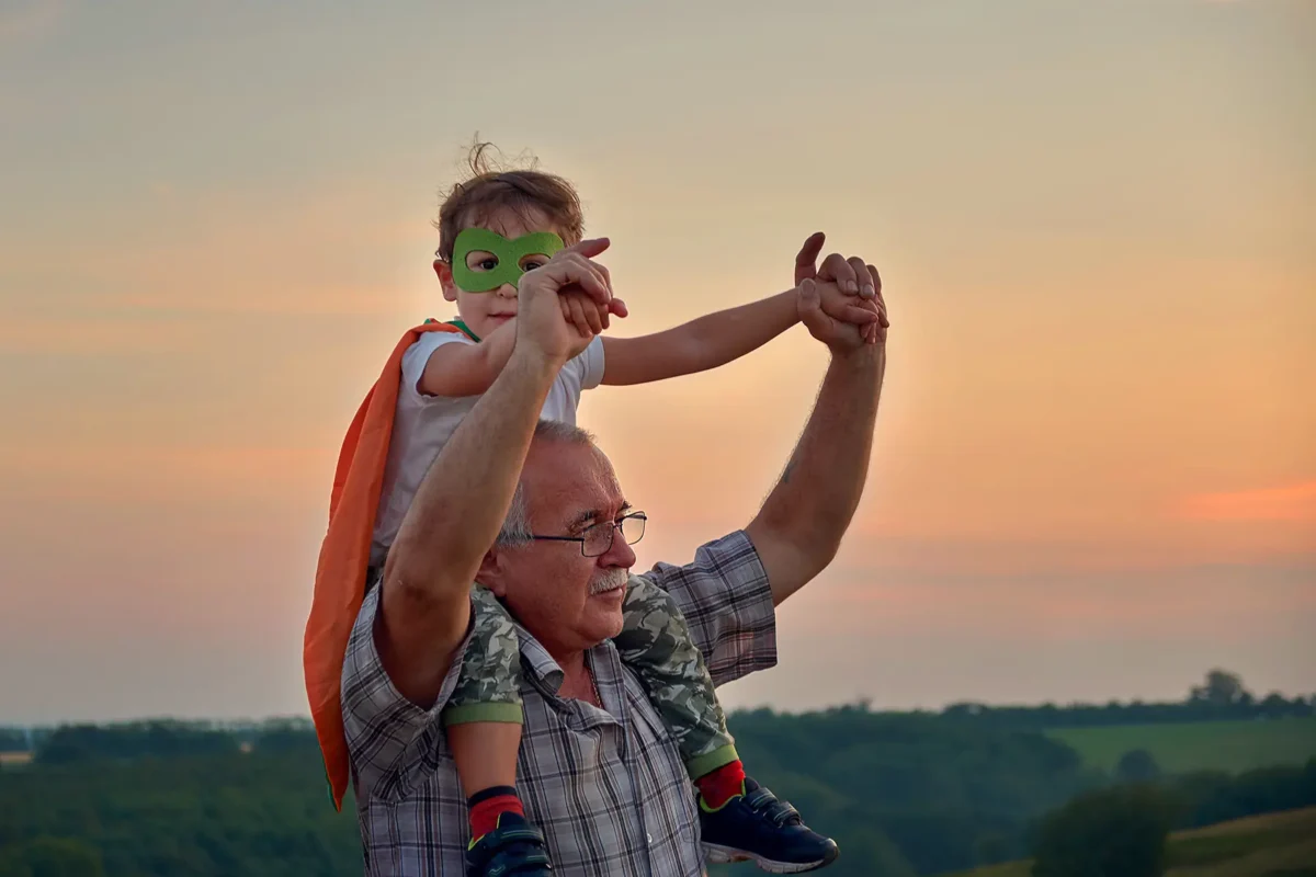 Großvater mit Enkel bei Sonnenuntergang als Zeichen für Fürsorge